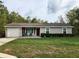 Charming single-story home with a well-manicured lawn, a red front door and an attached one car garage at 120 Fisher Ct, Ocklawaha, FL 32179