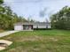 Quaint single-story home with a driveway, lush green lawn, and a manicured shrub in front at 120 Fisher Ct, Ocklawaha, FL 32179