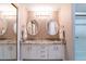 Bathroom features a double vanity with granite countertops, white cabinets, and dual round mirrors at 1228 Maria Ct, Lady Lake, FL 32159