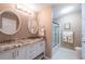 Bathroom features a double vanity with granite countertops, white cabinets, and glass door shower at 1228 Maria Ct, Lady Lake, FL 32159