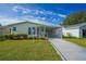 Charming single-story home with well-manicured lawn, carport and walkway under a bright blue sky at 1228 Maria Ct, Lady Lake, FL 32159