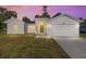 Home with manicured lawn, two car garage, and an inviting yellow front door at dusk at 12974 Se 42Nd Ct, Belleview, FL 34420