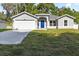 Charming home featuring a well-maintained lawn, a two-car garage, and an inviting bright blue front door at 12974 Se 42Nd Ct, Belleview, FL 34420