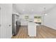 Open kitchen with white cabinets, stainless steel appliances, quartz countertops, and wood-look flooring at 12974 Se 42Nd Ct, Belleview, FL 34420