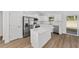 Spacious kitchen with white cabinetry, stainless steel appliances, quartz counters and island, and wood-look floors at 12974 Se 42Nd Ct, Belleview, FL 34420