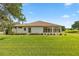 Backyard exterior with a sunroom addition, lush green lawn and a view of the golf course at 13015 Se 93Rd Cir, Summerfield, FL 34491
