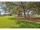 Picturesque backyard featuring mature trees with Spanish moss and well-maintained green lawn at 13015 Se 93Rd Cir, Summerfield, FL 34491