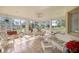 Bright sunroom with tile flooring, golf course views and comfortable white wicker furniture at 13015 Se 93Rd Cir, Summerfield, FL 34491