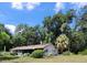 Rear exterior of a house with a screened porch and lots of mature trees at 13385 Ne 10Th Ct, Citra, FL 32113