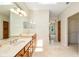 Bathroom with double sinks, marble countertops, and a view into an adjacent bedroom and walk-in closet at 13495 Se 93Rd Court Rd, Summerfield, FL 34491
