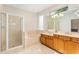 Bathroom featuring a glass-enclosed shower, soaking tub, and double vanities with a large mirror at 13495 Se 93Rd Court Rd, Summerfield, FL 34491