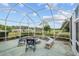 Relax in this screened lanai featuring a stone fire pit, seating, and scenic golf course views at 13495 Se 93Rd Court Rd, Summerfield, FL 34491