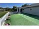 Backyard area with artificial grass, white picket fence, and enclosed patio at 14117 Sw 115Th Cir, Dunnellon, FL 34432