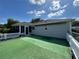 Backyard with synthetic grass and a white picket fence, offering low-maintenance outdoor space at 14117 Sw 115Th Cir, Dunnellon, FL 34432