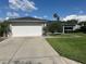 Home exterior featuring a two-car garage, mature landscaping, and well-maintained lawn at 14117 Sw 115Th Cir, Dunnellon, FL 34432