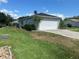 This home boasts a spacious two-car garage and a well-kept lawn with a beautiful blue sky at 14117 Sw 115Th Cir, Dunnellon, FL 34432