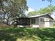 Home's backyard showing a screened-in porch, large tree, and green grass at 1675 Se 190Th Ave, Silver Springs, FL 34488