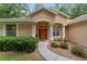Charming front entryway with an orange door, white pillars, and manicured landscaping at 18328 Sw 73Rd Loop, Dunnellon, FL 34432