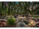 Backyard firepit area featuring stone pathway, outdoor furniture, and wooded backdrop at 200 Se 145Th St, Summerfield, FL 34491