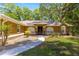 Charming single-story home featuring a manicured lawn, rock garden, and inviting arched entryway with a decorative glass door at 200 Se 145Th St, Summerfield, FL 34491