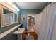 Charming bathroom featuring a pedestal sink, hardwood floors, large mirror, and a view into the hallway at 20549 9Th St, Mc Intosh, FL 32664