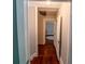 Hallway showcasing hardwood floors leading to a room with a crib at 20549 9Th St, Mc Intosh, FL 32664