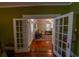 View of a living room with hardwood floors, white french doors, and olive green walls at 20549 9Th St, Mc Intosh, FL 32664