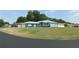 Inviting single-story light blue home with a well-kept lawn, complemented by lush landscaping and shade trees at 2909 Ne 25Th St, Ocala, FL 34470