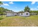 View of the backyard with a white exterior, metal roof, and minimal landscaping under a sunny sky at 4095 Sw 144Th St, Ocala, FL 34473