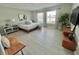 A bright bedroom with light wood floors, a queen-sized bed, and natural light from the large windows at 5667 Sw 92Nd Pl, Ocala, FL 34476
