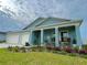 Charming blue home featuring a two-car garage, covered porch, and meticulously landscaped front yard at 5667 Sw 92Nd Pl, Ocala, FL 34476