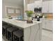Bright kitchen with a large island featuring a quartz countertop, a stainless steel sink, and seating for four at 5667 Sw 92Nd Pl, Ocala, FL 34476
