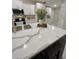 Modern kitchen island with waterfall quartz countertop, seating, and stainless steel sink at 5667 Sw 92Nd Pl, Ocala, FL 34476