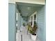 Charming blue porch with neutral columns, wood-look tile, and seating with potted flowers at 5667 Sw 92Nd Pl, Ocala, FL 34476