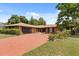 Lovely brick home with a red driveway, mature trees, and landscaping adding to the curb appeal at 6157 Ne 25Th Ave, Ocala, FL 34479