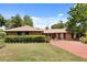 Charming brick home with a well-manicured lawn, mature trees, and a red brick driveway at 6157 Ne 25Th Ave, Ocala, FL 34479