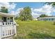 Expansive backyard featuring green lawn and mature trees, partially enclosed with a charming white fence at 6448 Sw 111Th Pl, Ocala, FL 34476