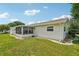 Back exterior view of home featuring screened-in porch, well-maintained lawn, and mature trees at 6448 Sw 111Th Pl, Ocala, FL 34476
