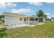 Exterior view of home featuring large screened-in porch, back patio, well-kept lawn, and white picket fence at 6448 Sw 111Th Pl, Ocala, FL 34476