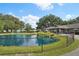 Scenic view of the pond with a fountain, lush greenery, and the community building in the background at 6448 Sw 111Th Pl, Ocala, FL 34476