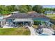 Aerial view of a patio with a table, chairs, and potted plants overlooking a pool and a manicured backyard at 7 Larch Dr, Ocala, FL 34480