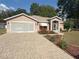 Charming single-story home featuring well-manicured landscaping, brick driveway, and a screened garage at 1001 Ne 22Nd Ave, Ocala, FL 34470