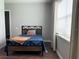 Bedroom with wood-look floors, window, and a bed with wood and metal frame and blue comforter at 10208 Se 170 Pl, Summerfield, FL 34491