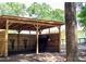 View of a wooden horse stall shelter and black horse; wooden fence and house in the background at 10208 Se 170 Pl, Summerfield, FL 34491