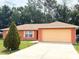 Single-story home with a two-car garage, orange stucco exterior, and well-manicured lawn at 14 Dogwood Drive Radl, Ocala, FL 34472