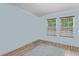 Light-filled bedroom with hardwood floors, light-blue walls, and two windows with blinds at 14330 Sw 79Th Ter, Ocala, FL 34473
