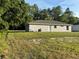 Side view of home showcases neutral siding, simple door, neat lawn, and trees in background at 14415 Sw 21St Pl, Ocala, FL 34481