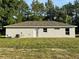 Side view of a single-story home features neutral siding, a standard door, and manicured lawn at 14415 Sw 21St Pl, Ocala, FL 34481