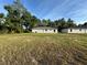 New home featuring a simple exterior design and a large lot surrounded by trees, under a sunny sky at 14415 Sw 21St Pl, Ocala, FL 34481