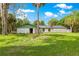Exterior shot of home featuring white brick, a lush green yard and mature palm trees at 17150 Se 168Th Ter, Weirsdale, FL 32195